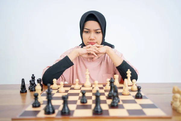 Mulher muçulmana chateada com a mão no queixo enquanto joga xadrez — Fotografia de Stock