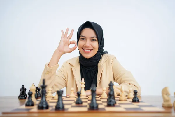 Hijab femme avec ok main geste tandis que assis jouer aux échecs — Photo