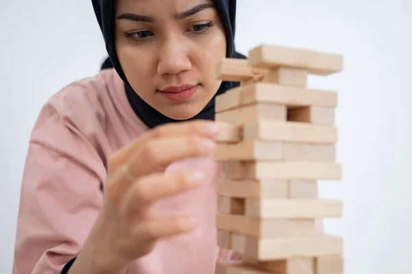 Женщина поднимает блоки, играя в башню из блоков — стоковое фото