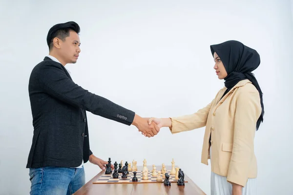 Uomo e donna in hijab che stringono la mano prima di giocare a scacchi — Foto Stock