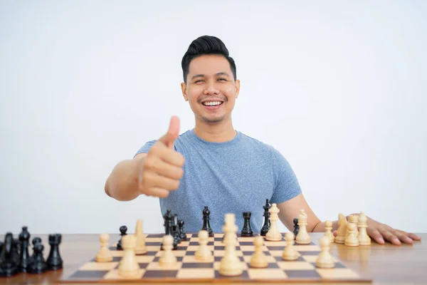 Mladý muž s palci nahoru sedí a hraje šachy — Stock fotografie