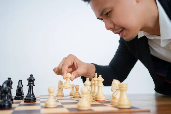 Asiatico uomo con mani holding pedone mentre gioca a scacchi — Foto Stock