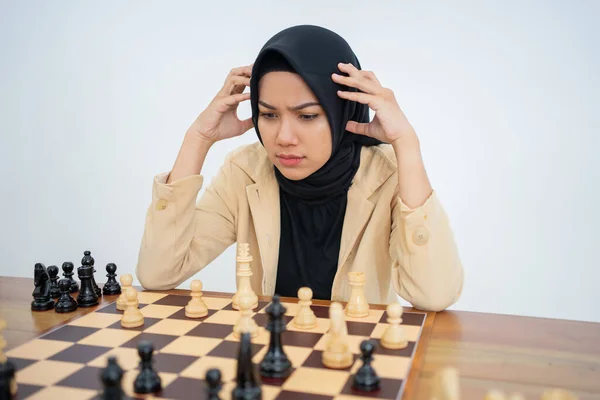 Hijab donna tenendo la testa pensando di passo durante la riproduzione di scacchi — Foto Stock