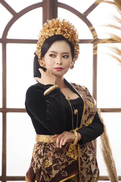 Женщина носит балийскую кебайю с ювелирными изделиями на фоне большого окна — стоковое фото