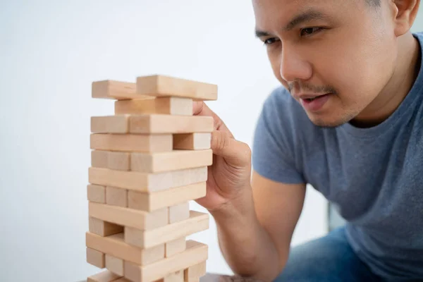 Man picking up blocks while playing tower of blocks — Stock Photo, Image