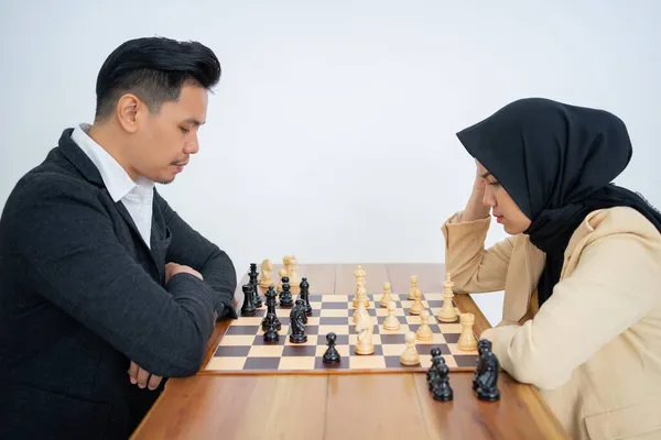 Homme en costume face à femme en hijab tout en jouant aux échecs — Photo