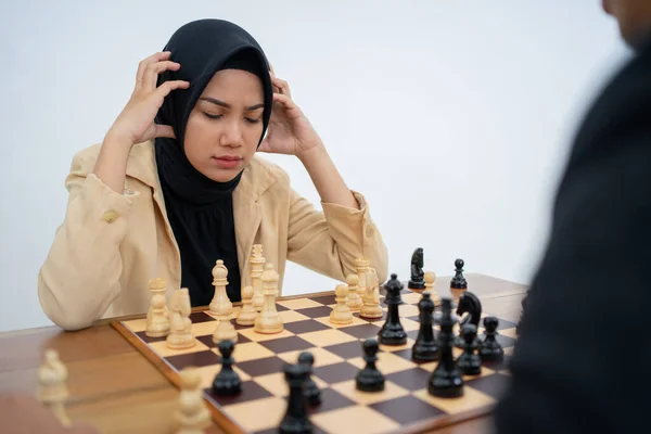 Woman in headscarf holding dizzy head while playing chess — Stock Photo, Image