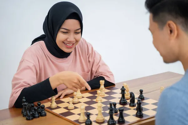 Donna musulmana sorridente con mano rivolta verso pezzi di scacchi — Foto Stock