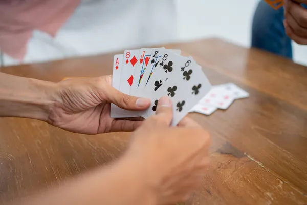 Duas mãos segurando cartas enquanto jogam cartas juntas — Fotografia de Stock