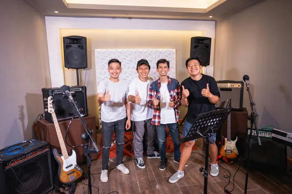 Four young asian men smiling with thumbs up in music rehearsal room — Stock Photo, Image