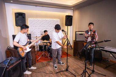 Çalışmaya başlamadan önce müzik aletlerini kontrol eden dört çocuk.