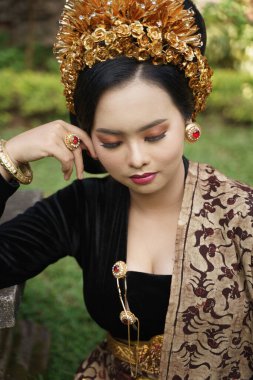 Balili kebaya giyen seksi kadın bahçede oturuyor.