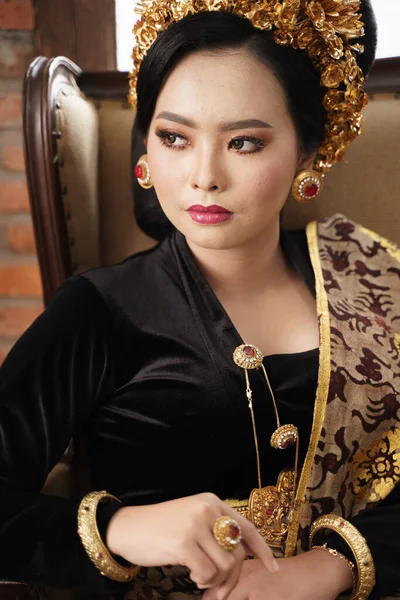 Woman sitting on sofa wearing jewelery and Balinese Kebaya — Stock Photo, Image