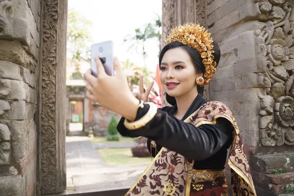 Mulher vestindo kebaya balinês tradicional leva uma selfie — Fotografia de Stock