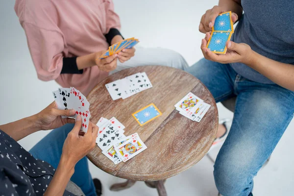 Drei Personen, die Karten halten, während sie gemeinsam Karten spielen — Stockfoto