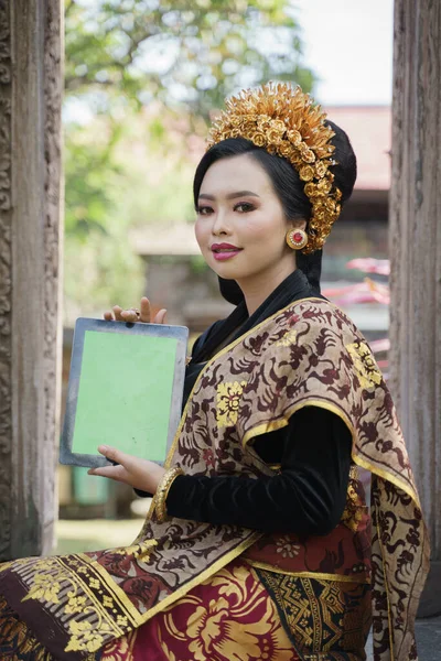 Frau trägt balinesischen Kebaya und zeigt ein digitales Tablet — Stockfoto