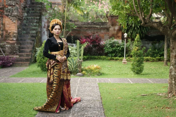 Mujer vestida con kebaya balinesa cerca de un árbol en el sendero —  Fotos de Stock