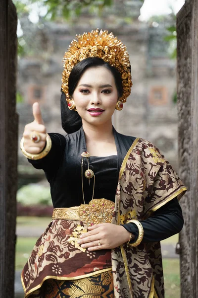 전통적 인 발리 옷을 입고 엄지손가락을 벌리고 있는 여성의 모습 — 스톡 사진