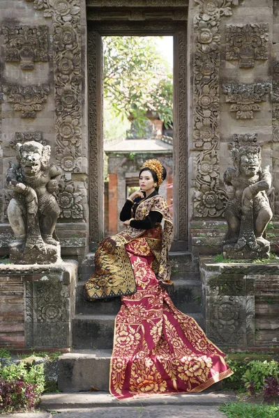 Femme assise portant kebaya balinais traditionnel avec long tissu tissé — Photo