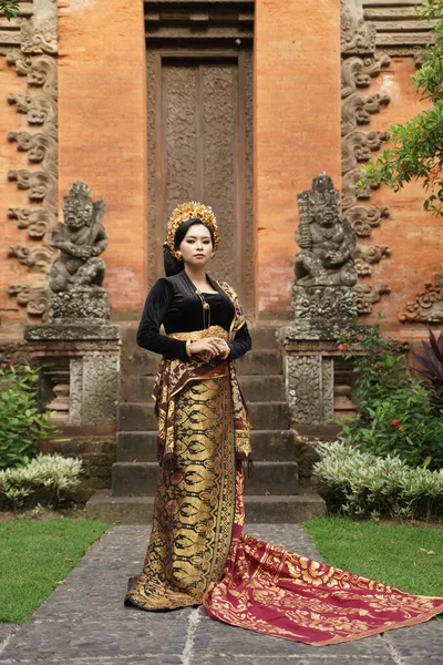 Azjatka ubrana w kebaya balijski i tkane tkaniny przeciwko świątyni — Zdjęcie stockowe