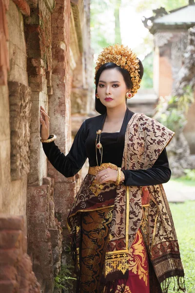 Vrouw het dragen van Balinese kebaya staan naast een reliëf muur — Stockfoto