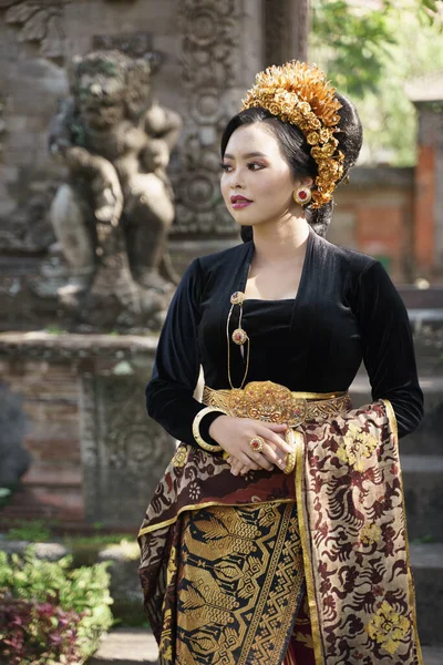 Wanita mengenakan kebaya hitam dengan patung di latar belakang — Stok Foto