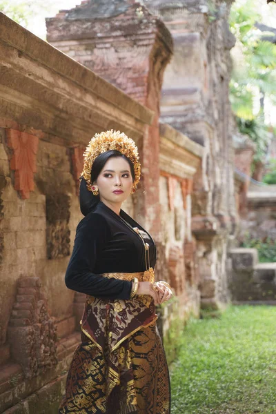 Mädchen mit balinesischem Kebaya steht in der Nähe des Tores der Reliefwand — Stockfoto