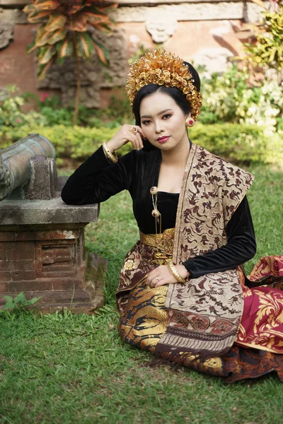 Ασιάτισσα που φοράει κεμπάγια από το Μπαλί και κάθεται στο γρασίδι — Φωτογραφία Αρχείου