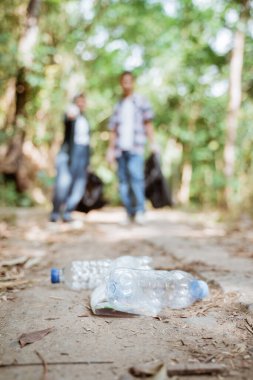 İki mutlu gönüllü genç çöpleri topluyor.