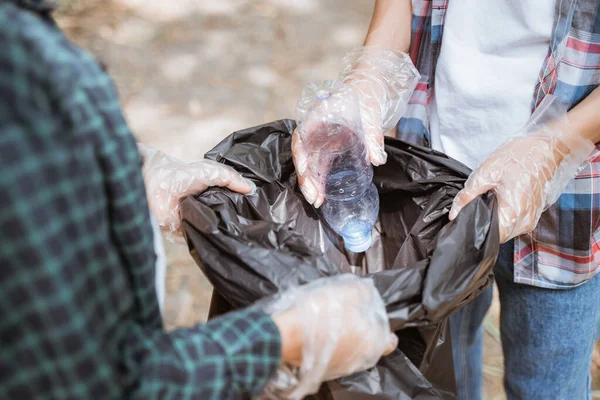 Ramasser à la main les déchets plastiques et les mettre dans le sac poubelle — Photo