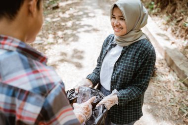 İki mutlu gönüllü genç çöpleri topluyor.