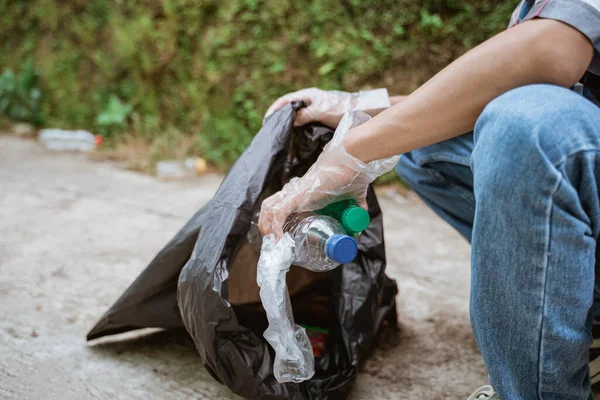 El plastik atıkları topluyor ve çöp torbasına koyuyor. — Stok fotoğraf