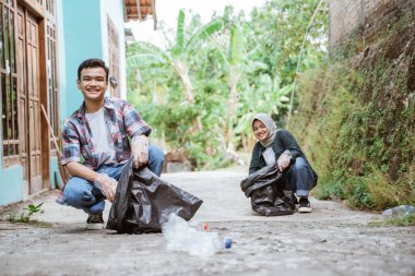 İki mutlu gönüllü genç çöpleri topluyor.