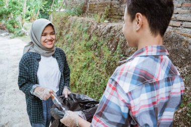 İki mutlu gönüllü genç çöpleri topluyor.