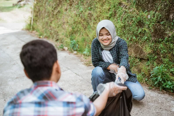İki mutlu gönüllü genç çöpleri topluyor.