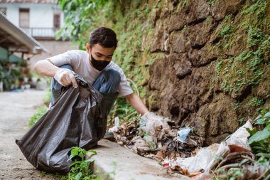 Genç gönüllüler çöpleri toplayarak çevreyi temiz tutuyorlar.