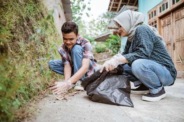 İki mutlu gönüllü genç çöpleri topluyor.