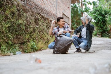 İki mutlu gönüllü genç çöpleri topluyor.