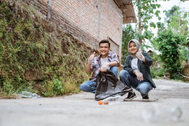 İki mutlu genç gönüllü çöpleri karıştırıyor.