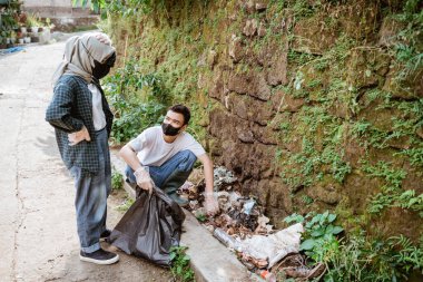 İki mutlu gönüllü genç çöpleri topluyor.