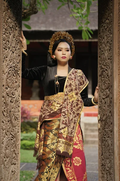 Mulher vestindo kebaya balinês segurando esculpida porta de madeira — Fotografia de Stock