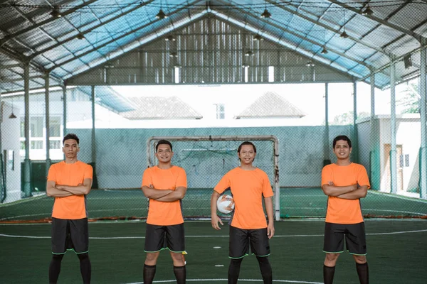 Vier futsal spelers die op een rij staan en de bal dragen — Stockfoto