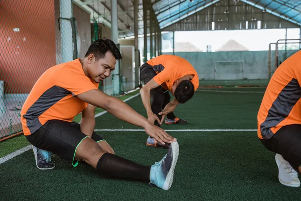 Futsal jugadores estiran sus piernas con las manos tocando los zapatos —  Fotos de Stock