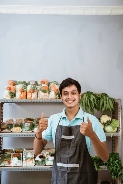 Усміхнений чоловік з двома великими пальцями на фоні рослинних продуктів — стокове фото