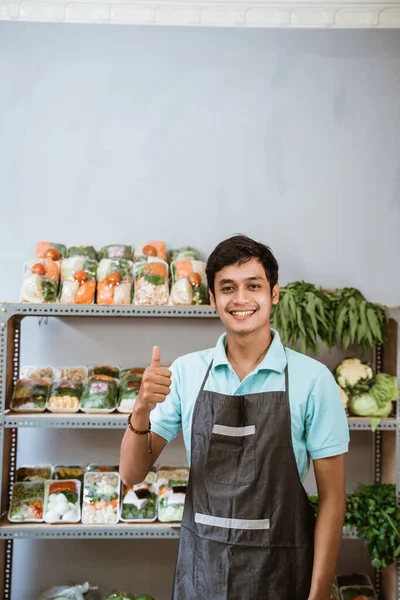 Lächelnder Mann mit Daumen hoch mit Gemüseprodukten im Hintergrund — Stockfoto