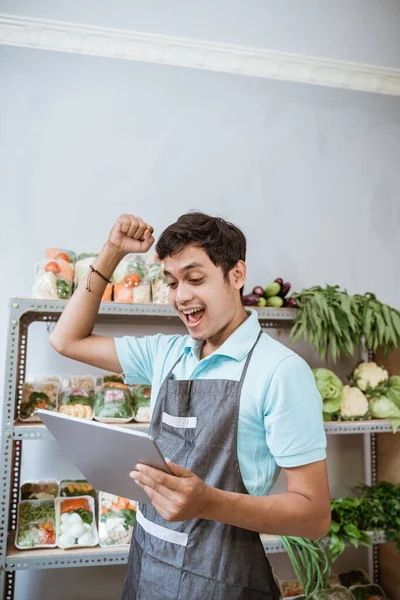 Asian man selling vegetables with raised hands using a pad — Stock Photo, Image
