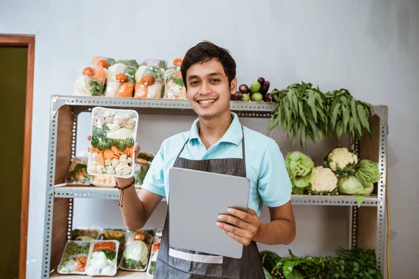 Man grönsakshandlare visar grönsaker medan du håller en digital tablett — Stockfoto