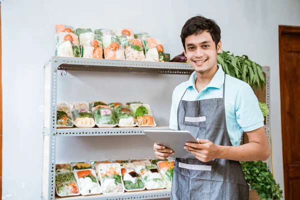 Hombre vendiendo verduras sonriendo mientras usa una tableta digital —  Fotos de Stock