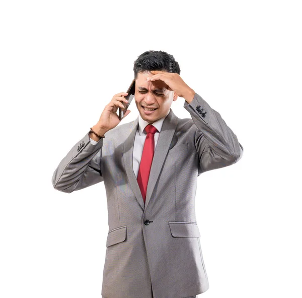 Stresli, takım elbiseli genç adam telefon yaparken başını tutuyor. — Stok fotoğraf