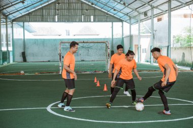 Dört futsal oyuncusu topla antrenman yapıyor.